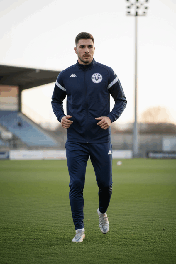 Joueur du JS Wenheck Saint-Avold portant le survêtement officiel du club sur le terrain de football, entraînement en tenue professionnelle.